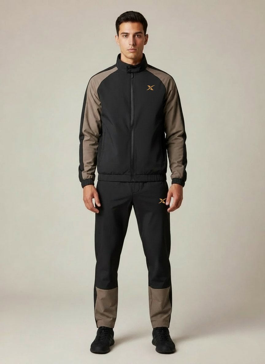 L'ensemble Raglan Shift porté, vu de face : veste noire zippée, manches raglan taupe, panneau taupe sur le bas de jambe.