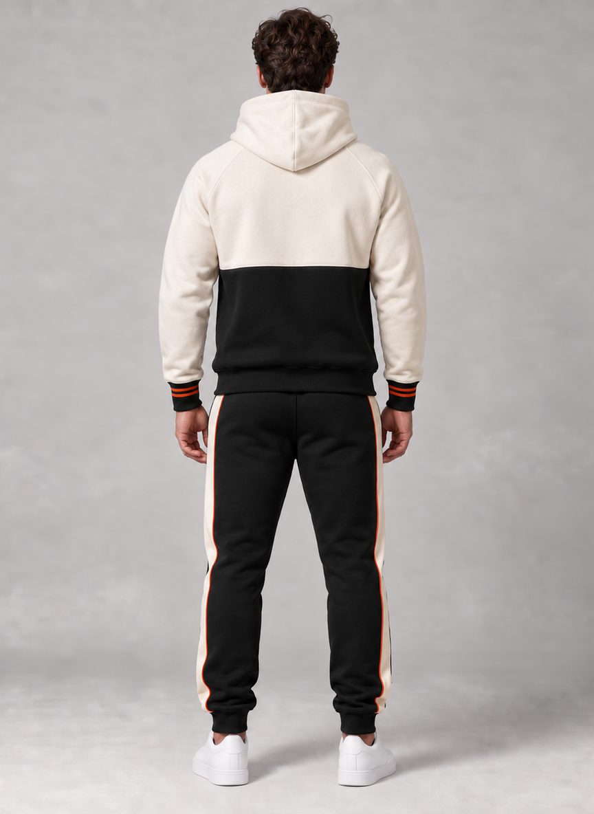 Le même ensemble vu de dos : capuche et haut du dos ivoire, bas du dos noir, sans motif ; le jogger est noir avec la bande ivoire liserée d'orange sur le côté.