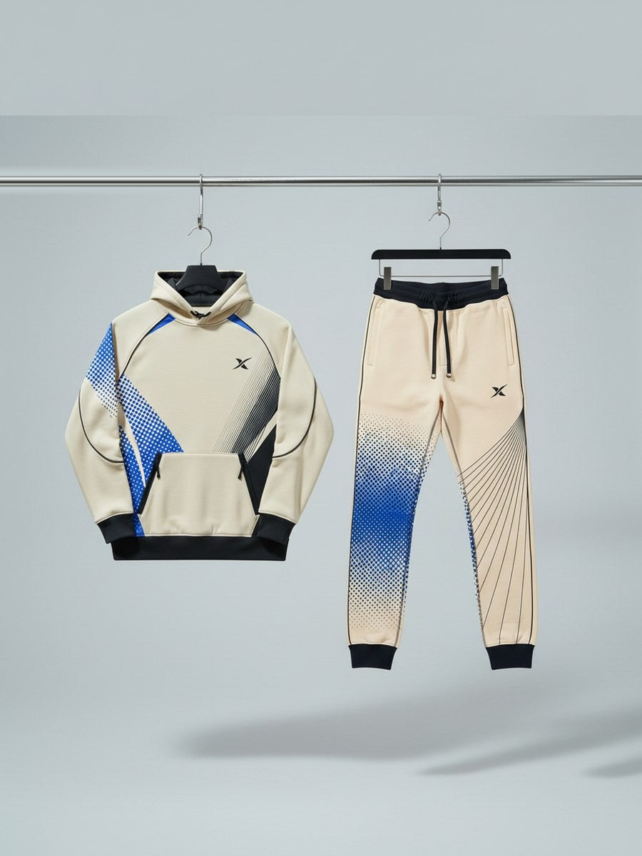 An ivory hoodie with marlin blue panels and its matching joggers, hanging on a workshop rail