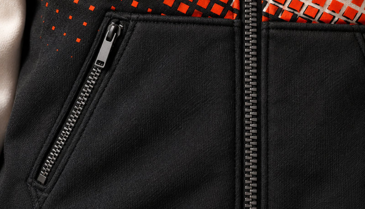 Gros plan sur la poche kangourou séparée par le zip central, avec un zip en biais sur la moitié visible.