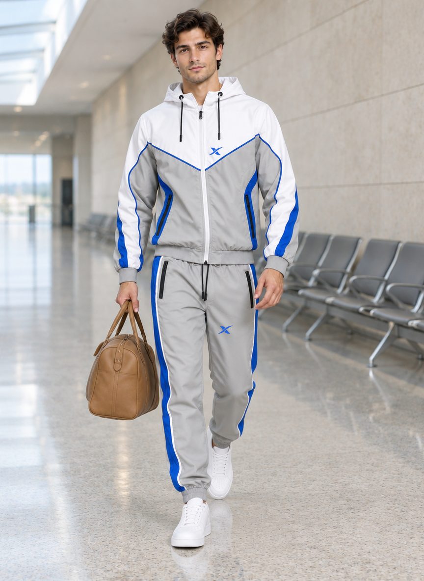 Le mannequin traverse un couloir d'aéroport, sac à la main, vêtu de l'ensemble Chevron Shell Capuche.